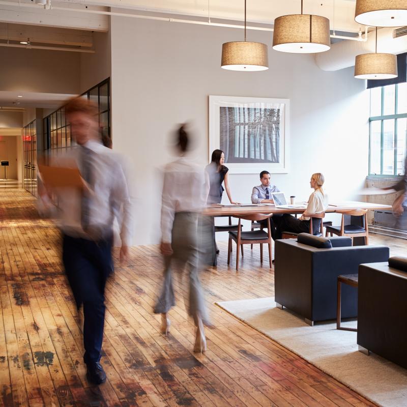 Image of busy office with workers walking through hallways