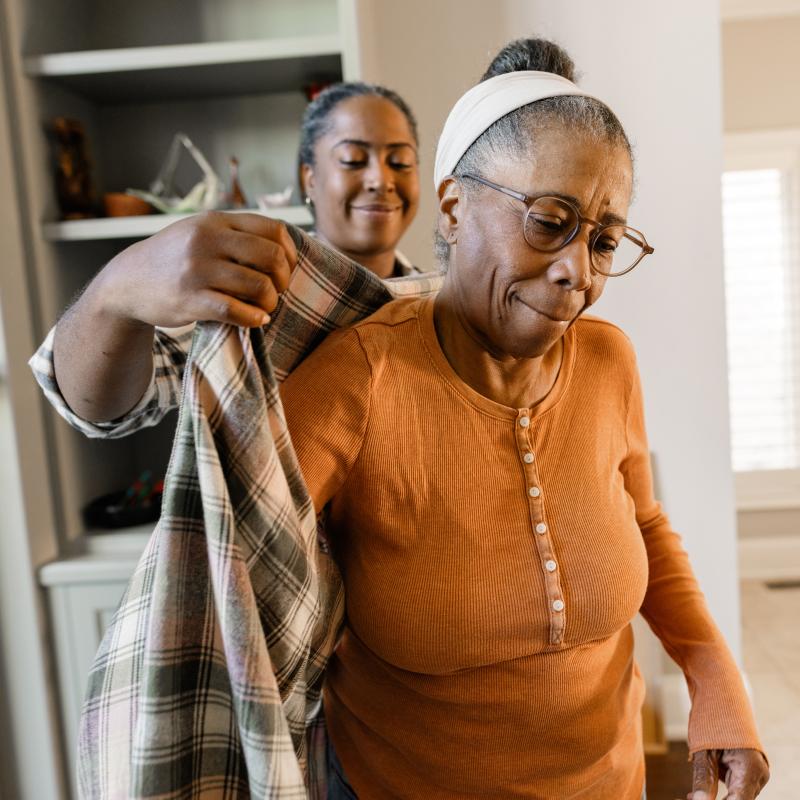 Daughter helping her elderly mother put on her coat