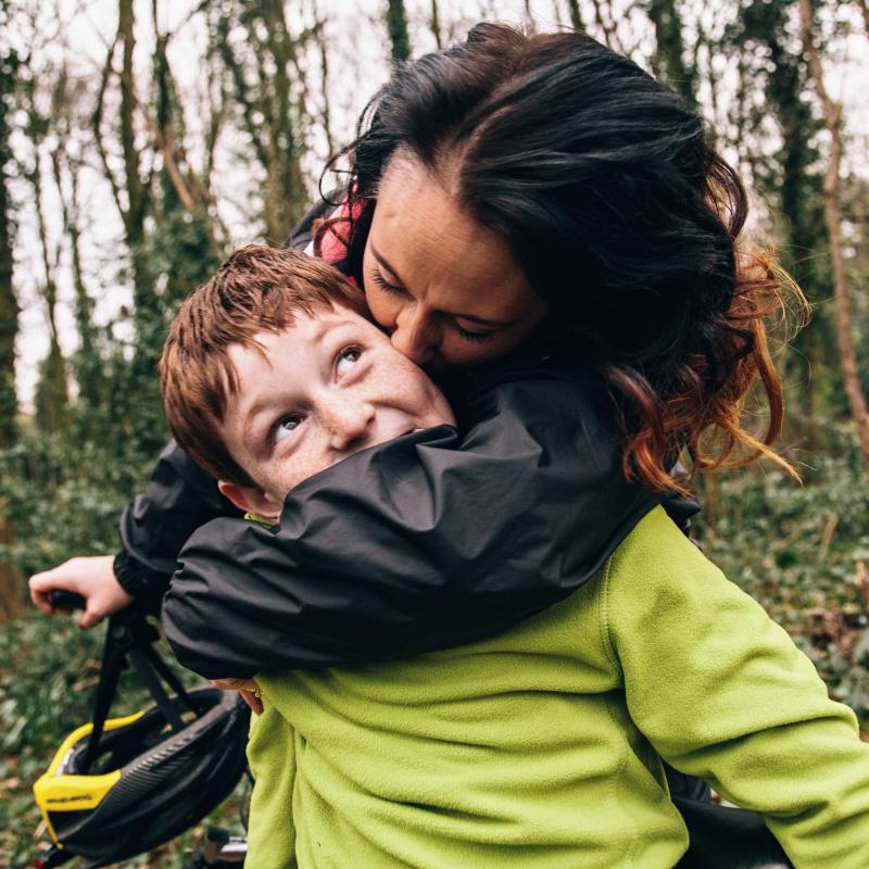 Mom kissing son on bike ride.