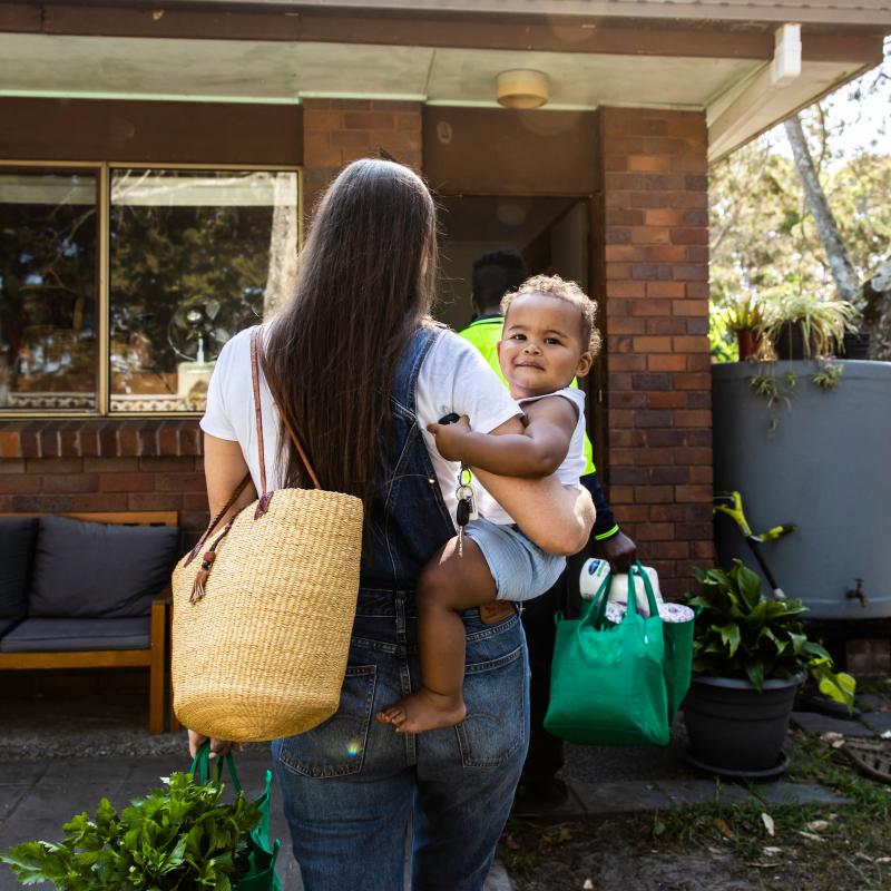 Mother holding daughter walking up to front door.