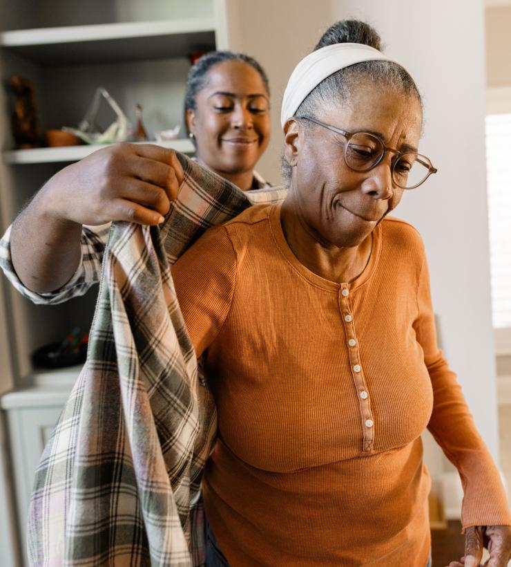 Hija ayudando a su madre anciana a ponerse el abrigo